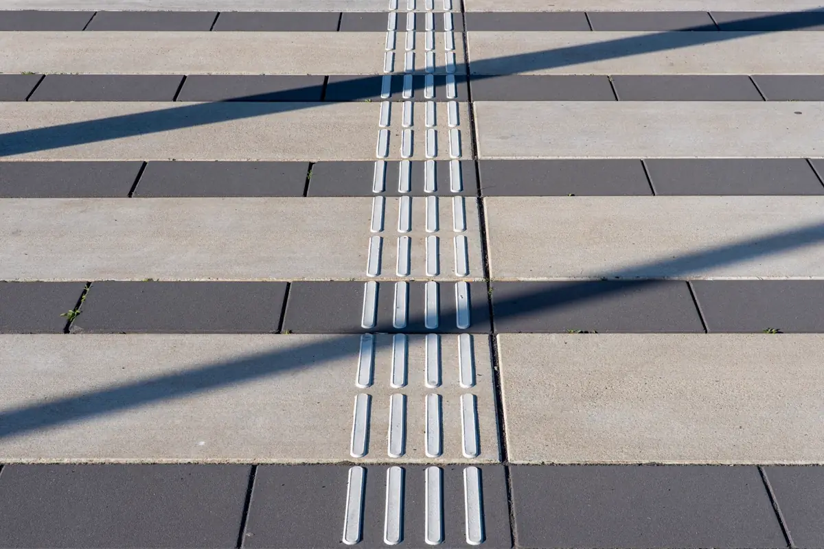 Faixa de piso tátil direcional em calçada de placas de concreto