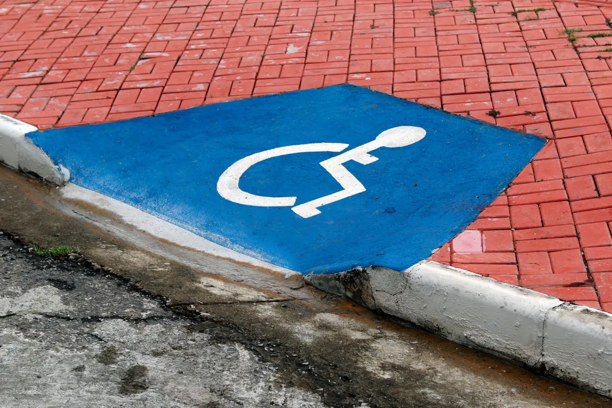 Símbolo internacional de acesso pintado em azul no piso de uma vaga, junto ao meio-fio