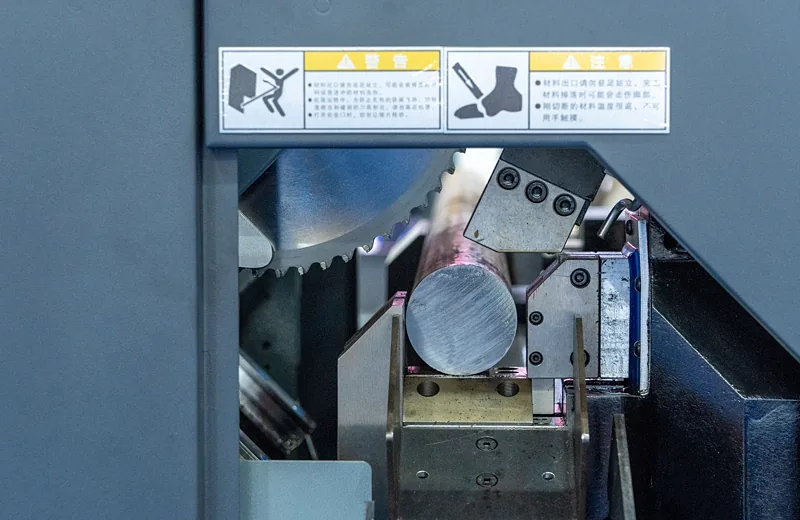Máquina industrial com proteção fixa e etiquetas de advertência de segurança na zona de corte