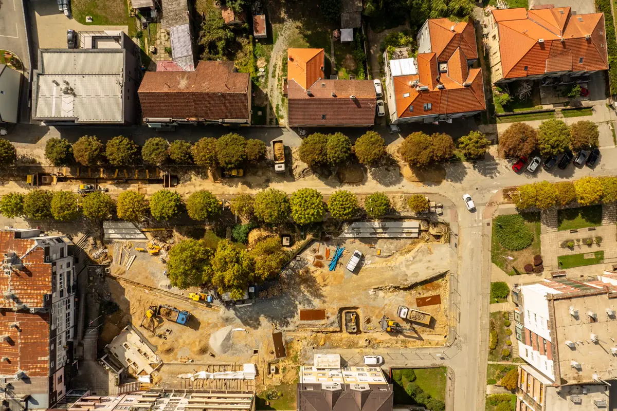 Vista aérea de um canteiro de obra cercado por casas e prédios residenciais